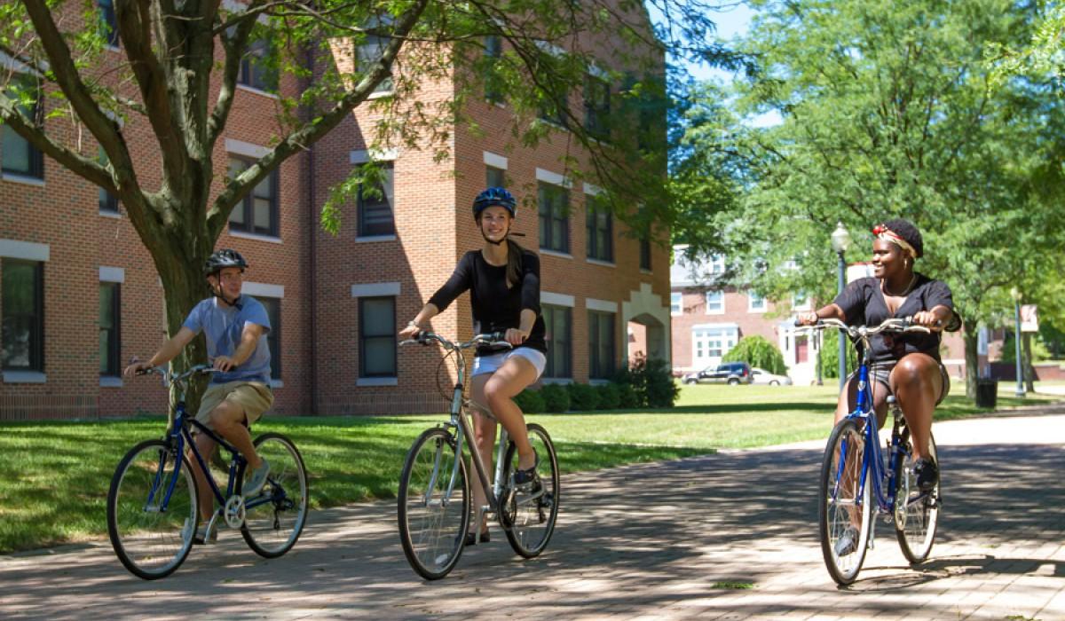 Students riding bikes down Alumni Way